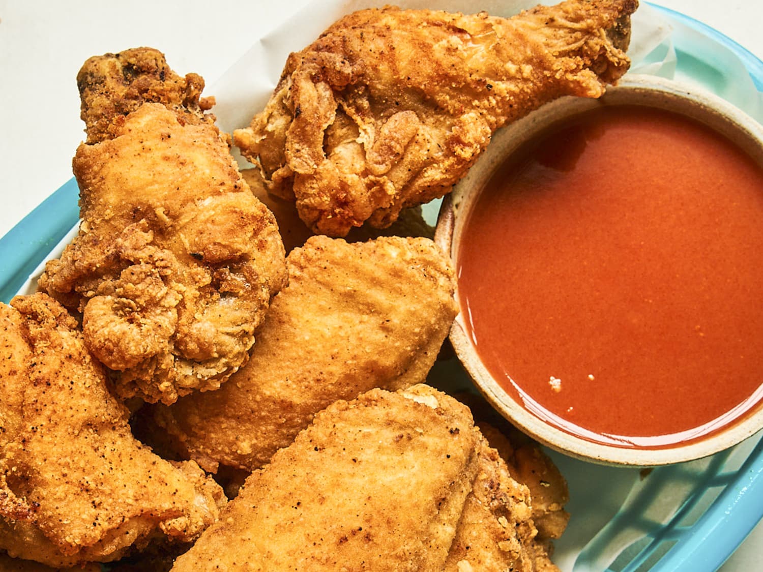 Crispy, golden chicken wings with a big bowl of spicy hot sauce